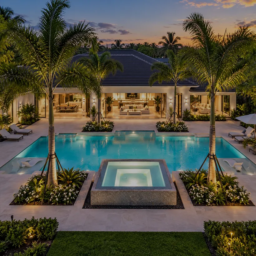 Acreage Homes in Naples, Florida: lit pool and raised spa at dusk behind a single-story estate home in Livingston Woods, Naples, Florida