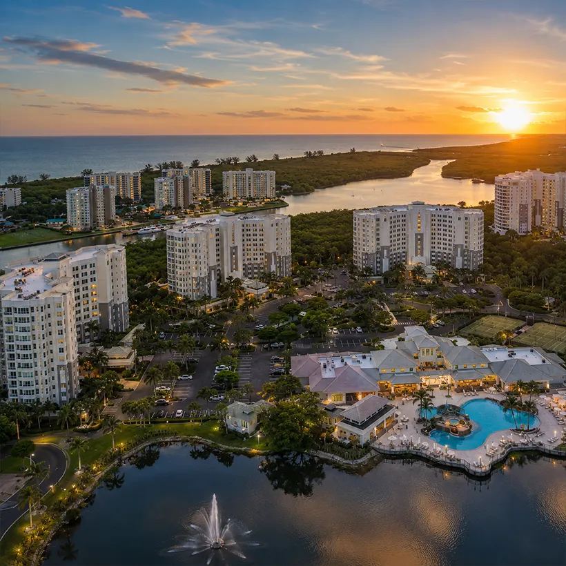New Construction Condos in Naples, Florida: aerial view at sunset of the high-rise towers, resort pool and lake at The Dunes, North Naples, Florida