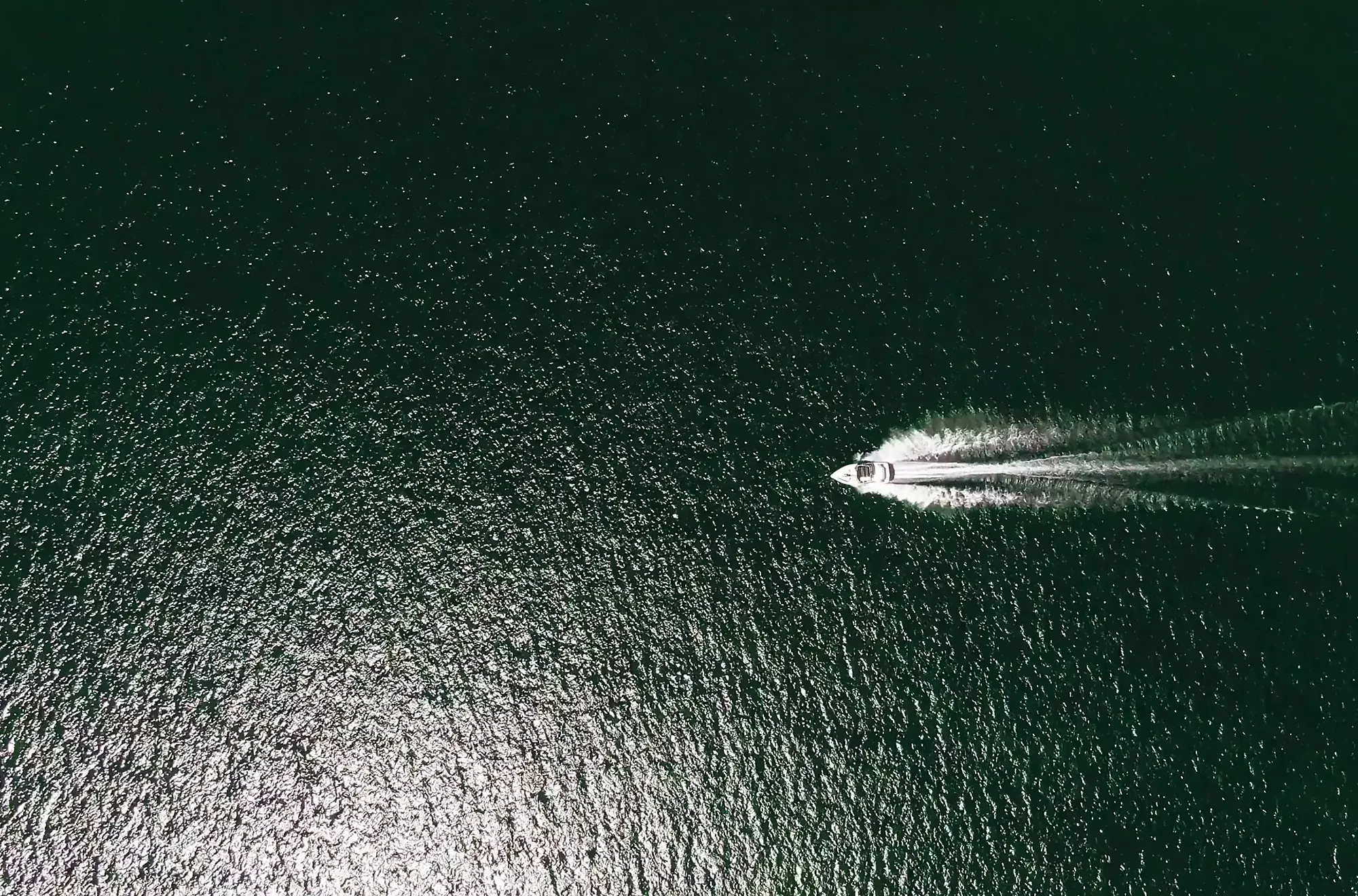 Motor yacht running across open Gulf water seen from above, the unrestricted route that direct Gulf access gives Naples boaters