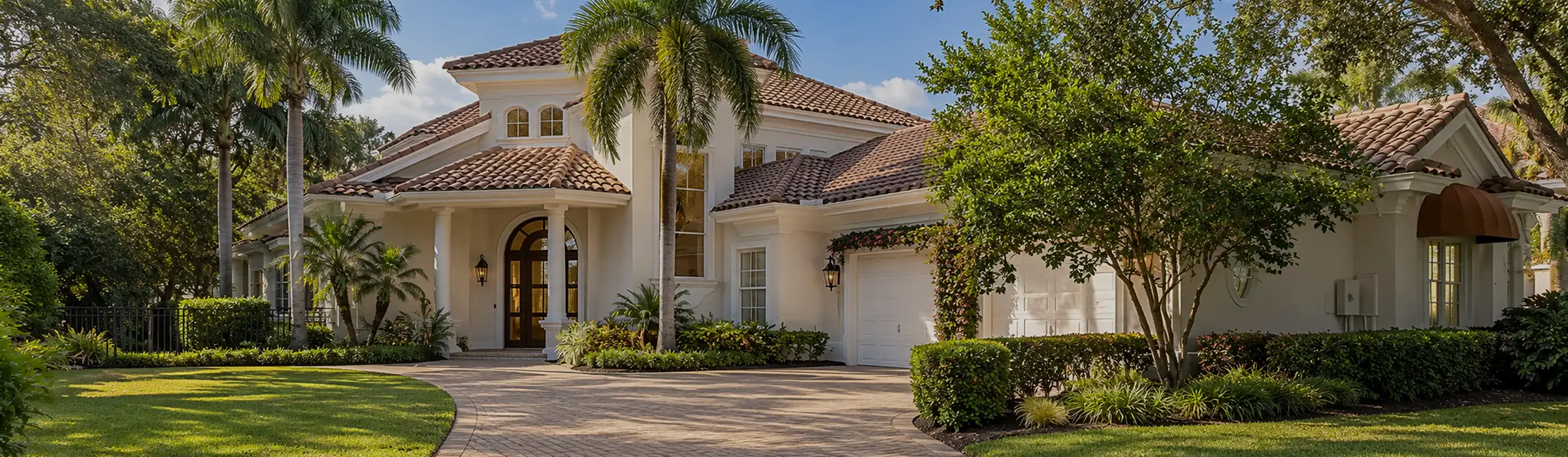 Mediterranean-style house with a tile roof and paver drive in a gated community in Naples, Florida