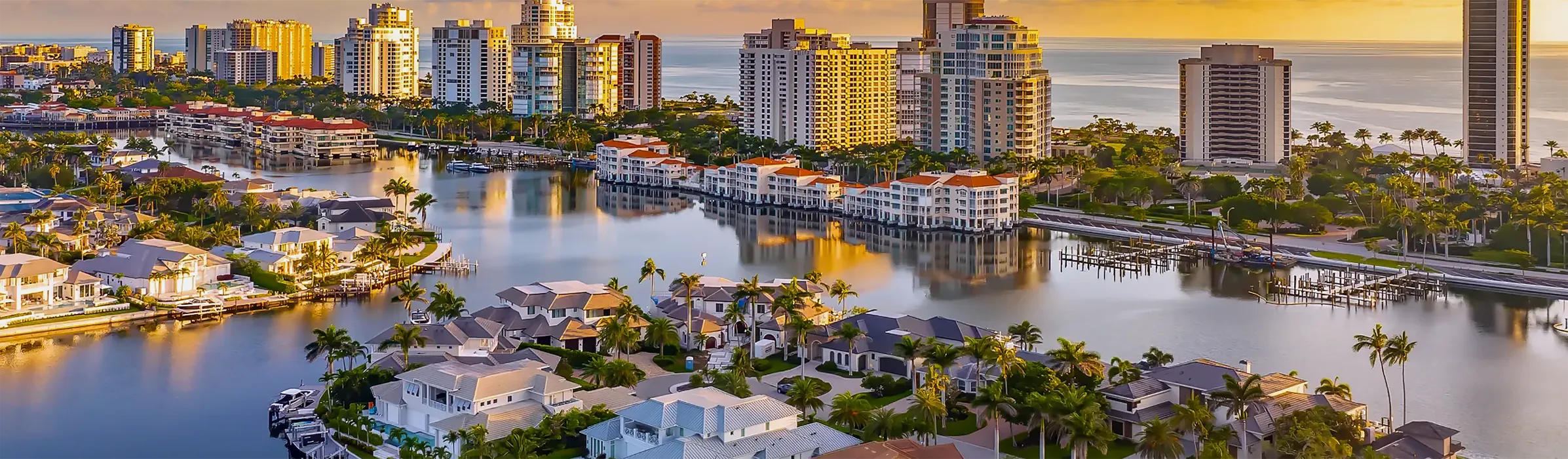 Aerial view at sunset of waterfront homes and condominium towers along the bay in Naples, Florida, the choices our buyers discover with us