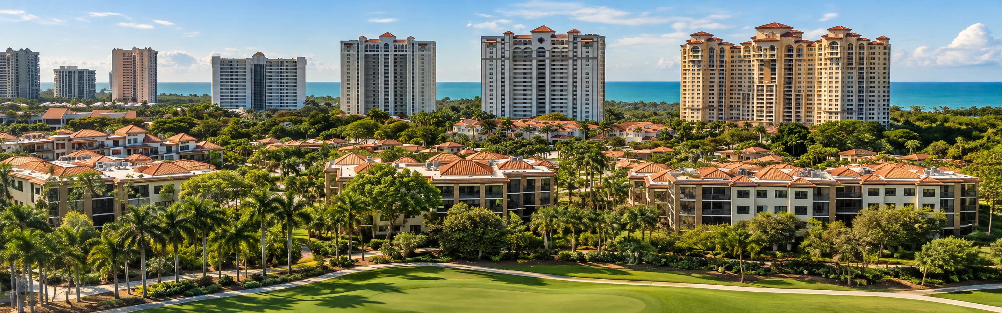 Pelican Bay condominium towers rising above mid-rise buildings and a golf course, with the Gulf beyond, Naples, Florida